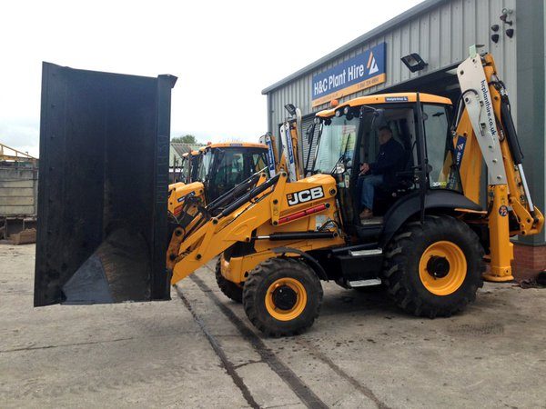 JCB 3CX with its side-tip bucket raised outside the H&C workshop