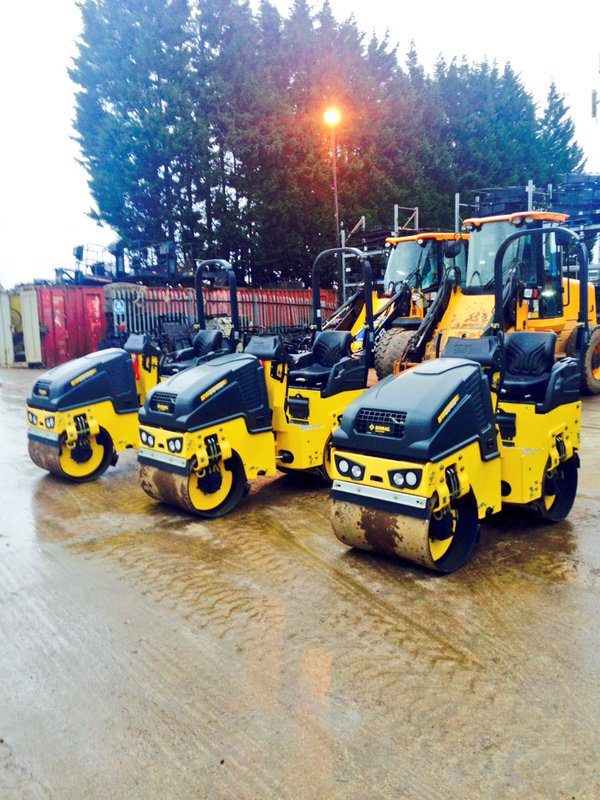 Three yellow tandem rollers lined up in the yard