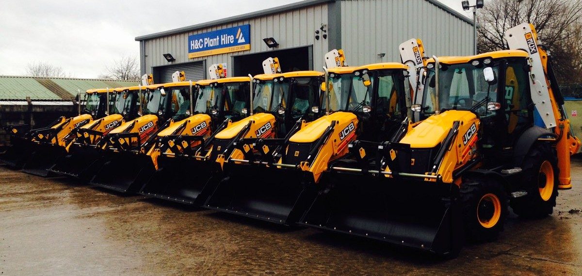 Row of yellow H&C JCB backhoe loaders outside the workshop