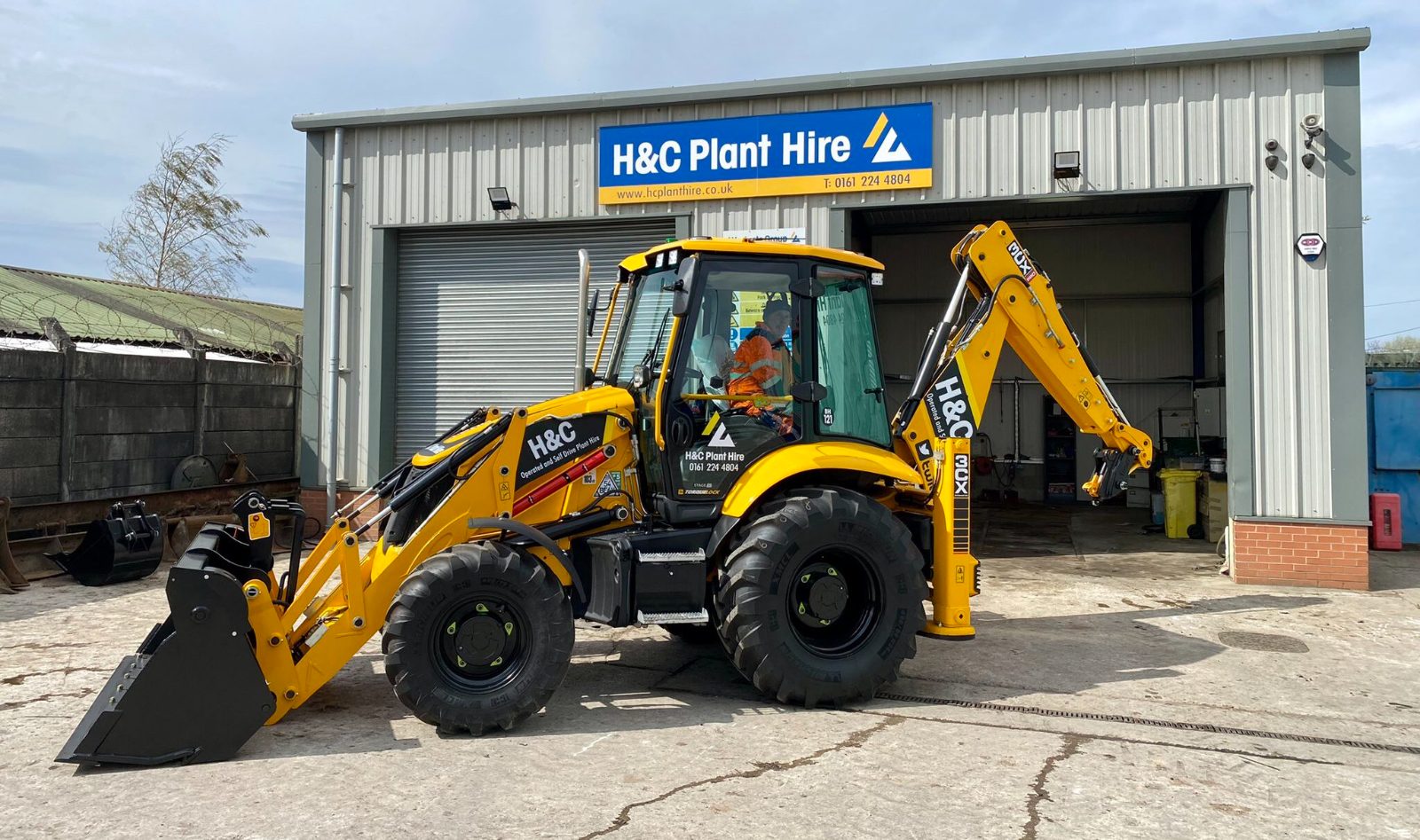 JCB 3CX parked in front of the H&C Plant Hire workshop