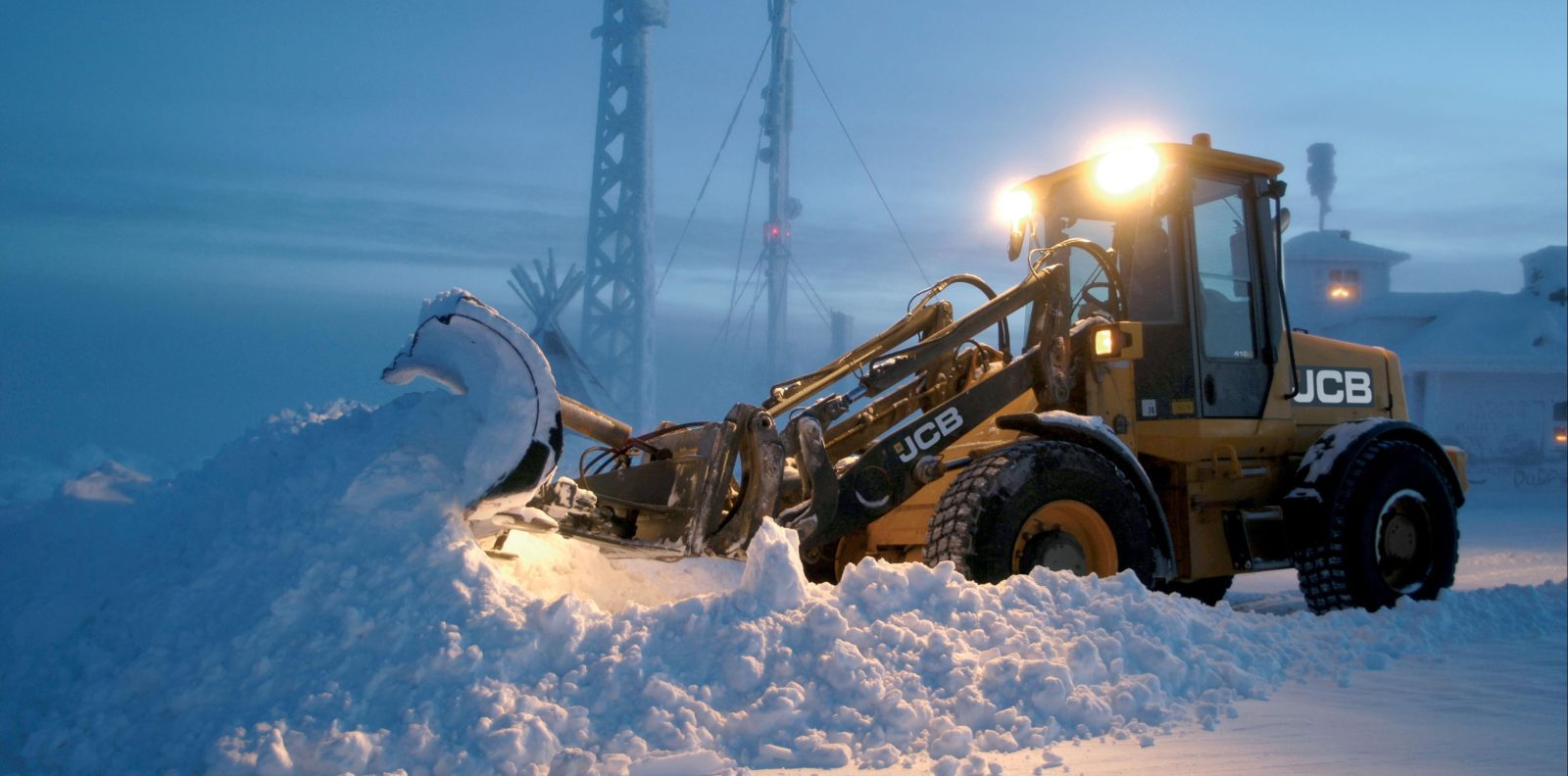 JCB loading shovel clearing deep snow with a front-mounted plough
