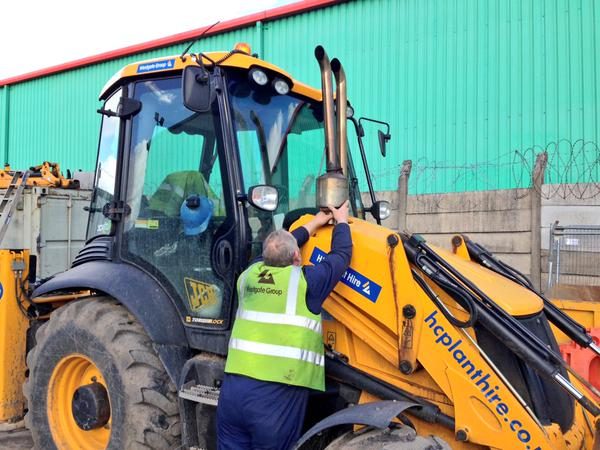 Engineer working beside the cab of a JCB 3CX backhoe loader